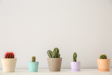 Photo of Beautiful cacti in flowerpots on white table indoors