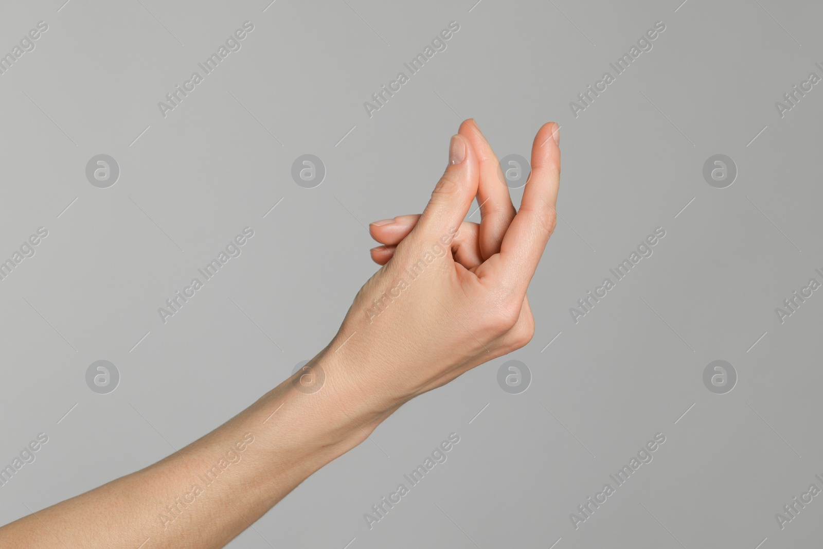 Photo of Woman snapping her fingers on light grey background, closeup. Bad habit