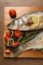 Delicious baked fish and vegetables on wooden table, top view