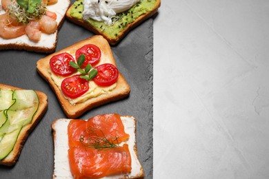 Different delicious toasts on light grey table, space for text