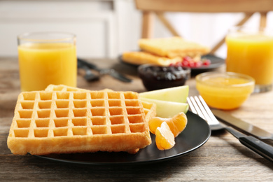 Waffles with fruits served on wooden table. Delicious breakfast
