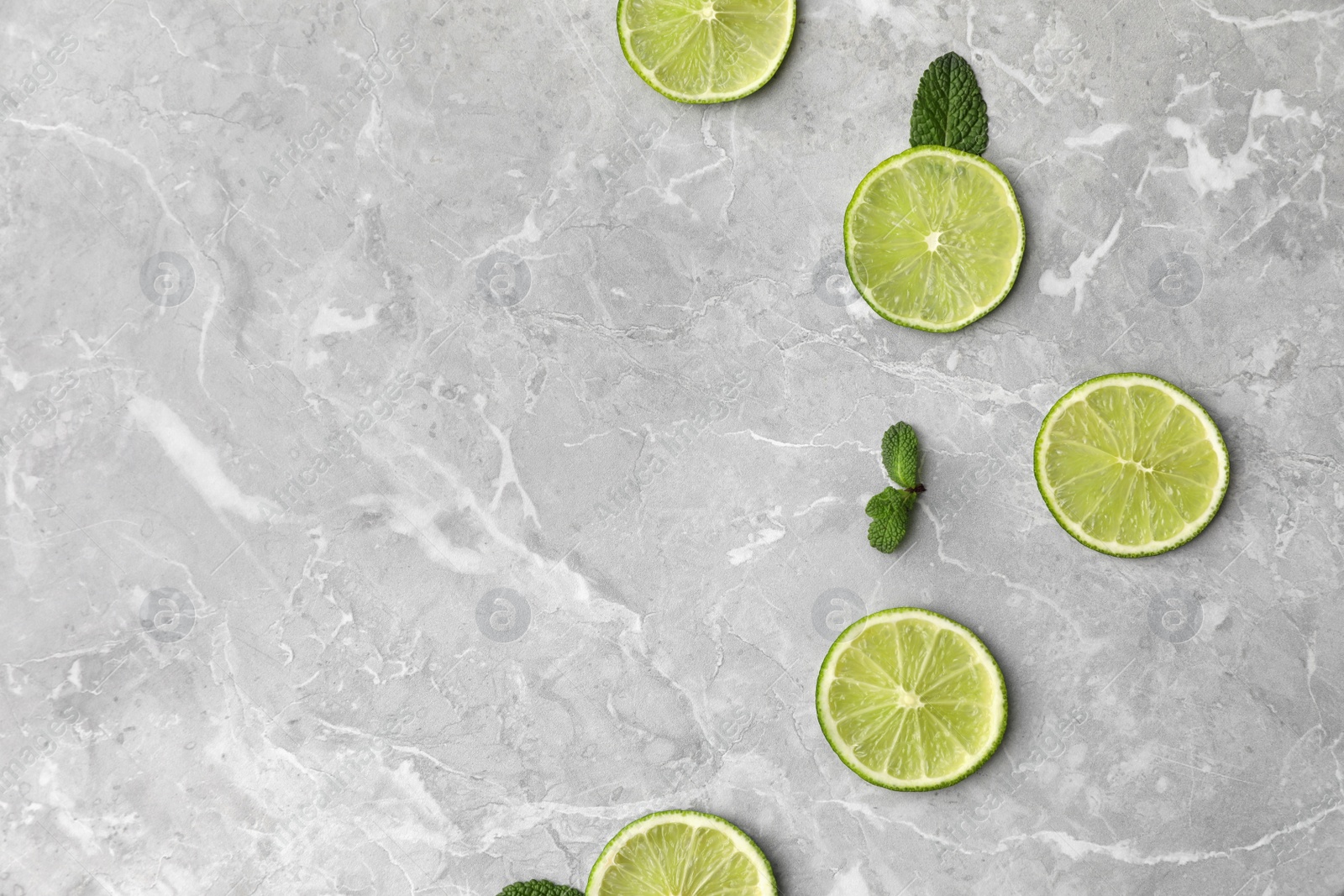 Photo of Flat lay composition with slices of fresh juicy limes on marble table. Space for text