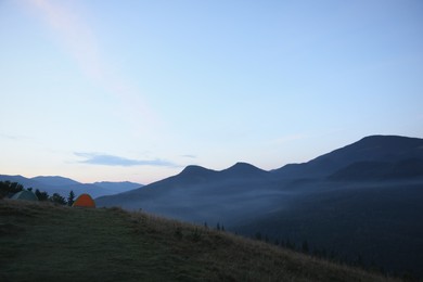 Photo of Two color camping tents on hill in mountains
