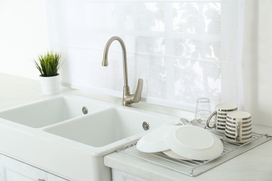 Photo of Clean dishes drying on rack in modern kitchen