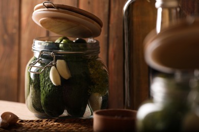 Photo of Glass jar with fresh cucumbers ready for canning on wooden table
