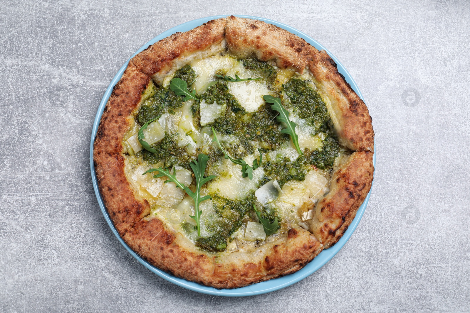 Photo of Delicious pizza with pesto, cheese and arugula on grey table, top view