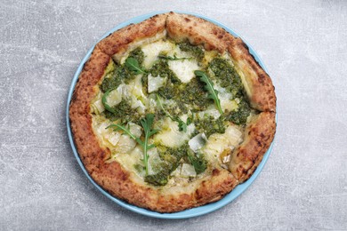 Photo of Delicious pizza with pesto, cheese and arugula on grey table, top view