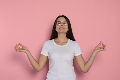 Photo of Young woman meditating on pink background. Zen concept