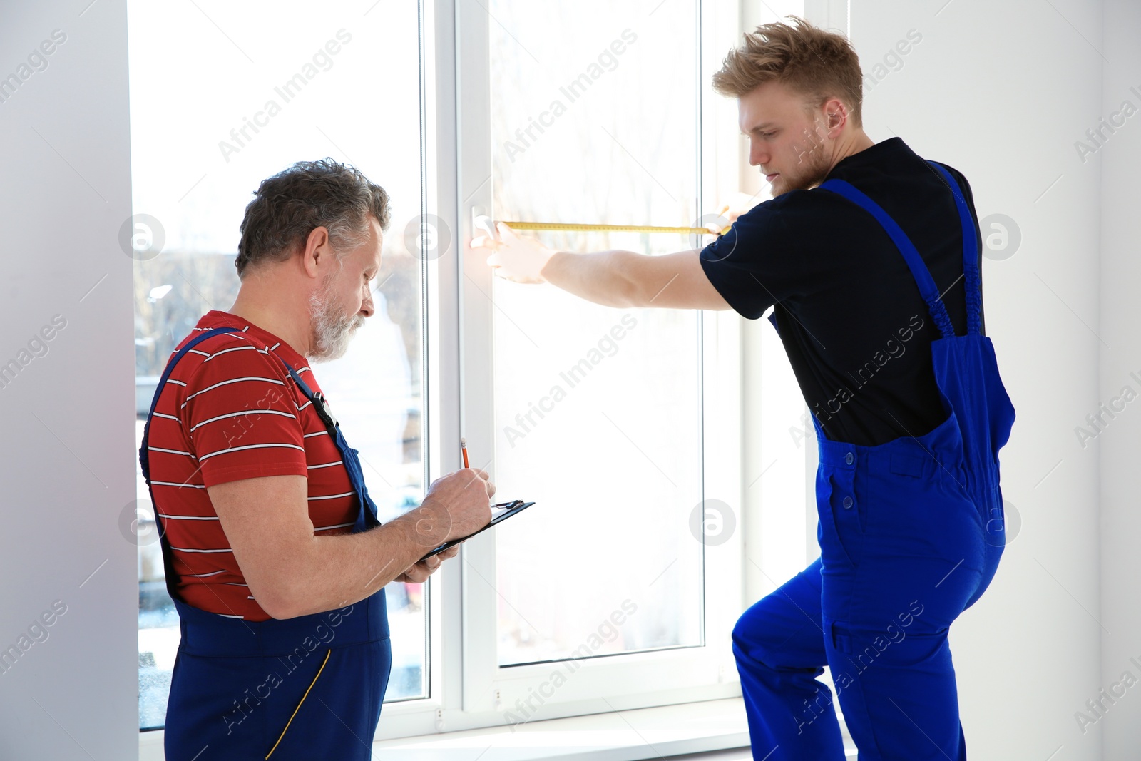 Photo of Service men measuring window for installation indoors