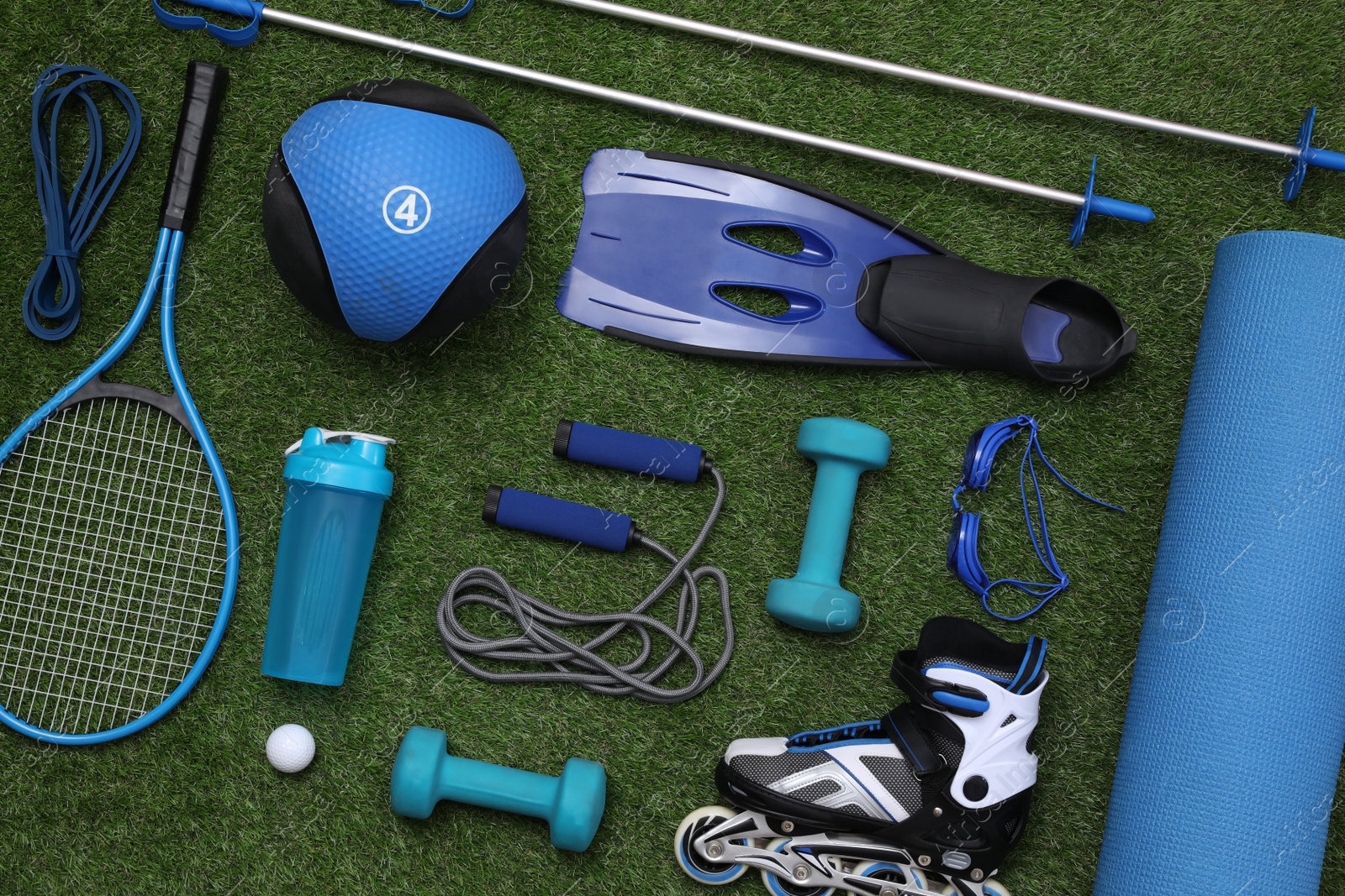 Photo of Different sport equipment on green grass, flat lay