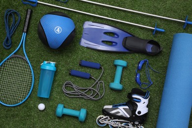 Photo of Different sport equipment on green grass, flat lay