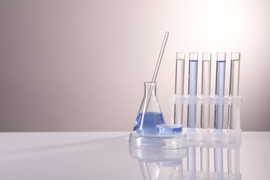 Laboratory analysis. Different glassware on table against light background, space for text