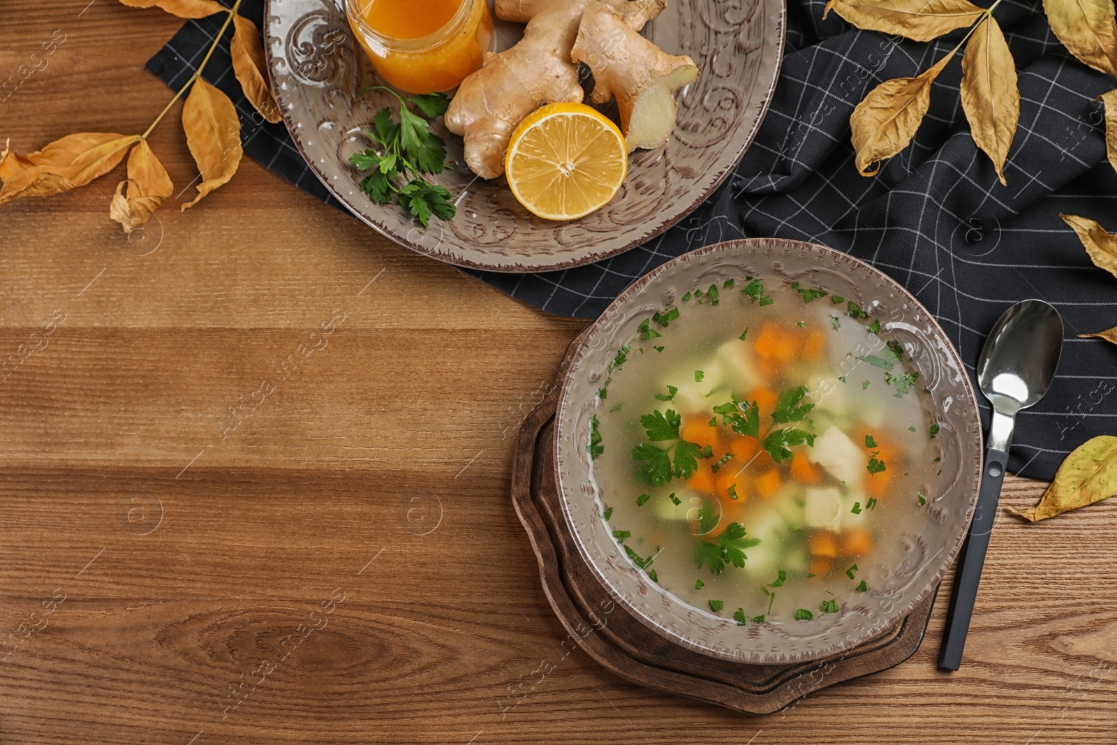 Photo of Flat lay composition with bowl of fresh homemade soup to cure flu and space for text on wooden background