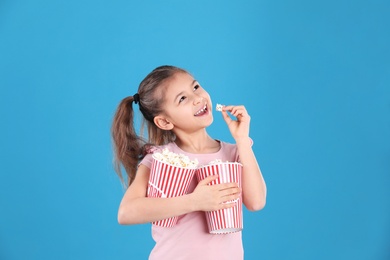 Cute little girl with popcorn on color background