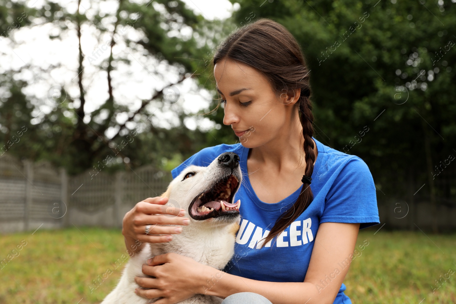 Photo of Female volunteer with homeless dog at animal shelter outdoors