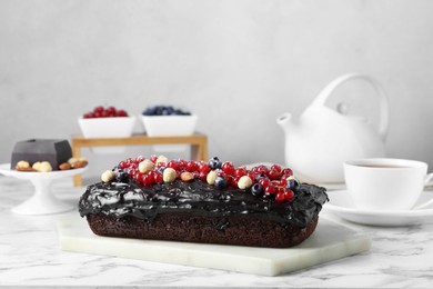 Photo of Delicious chocolate sponge cake with berries and nuts on white marble table