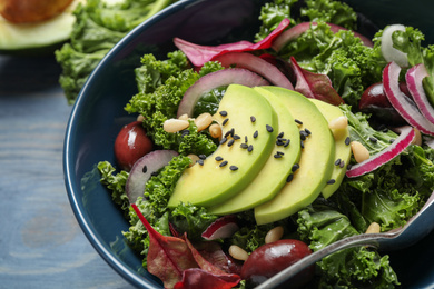 Tasty fresh kale salad on blue wooden table, closeup