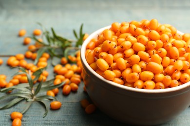 Photo of Ripe sea buckthorn berries on blue wooden table, closeup