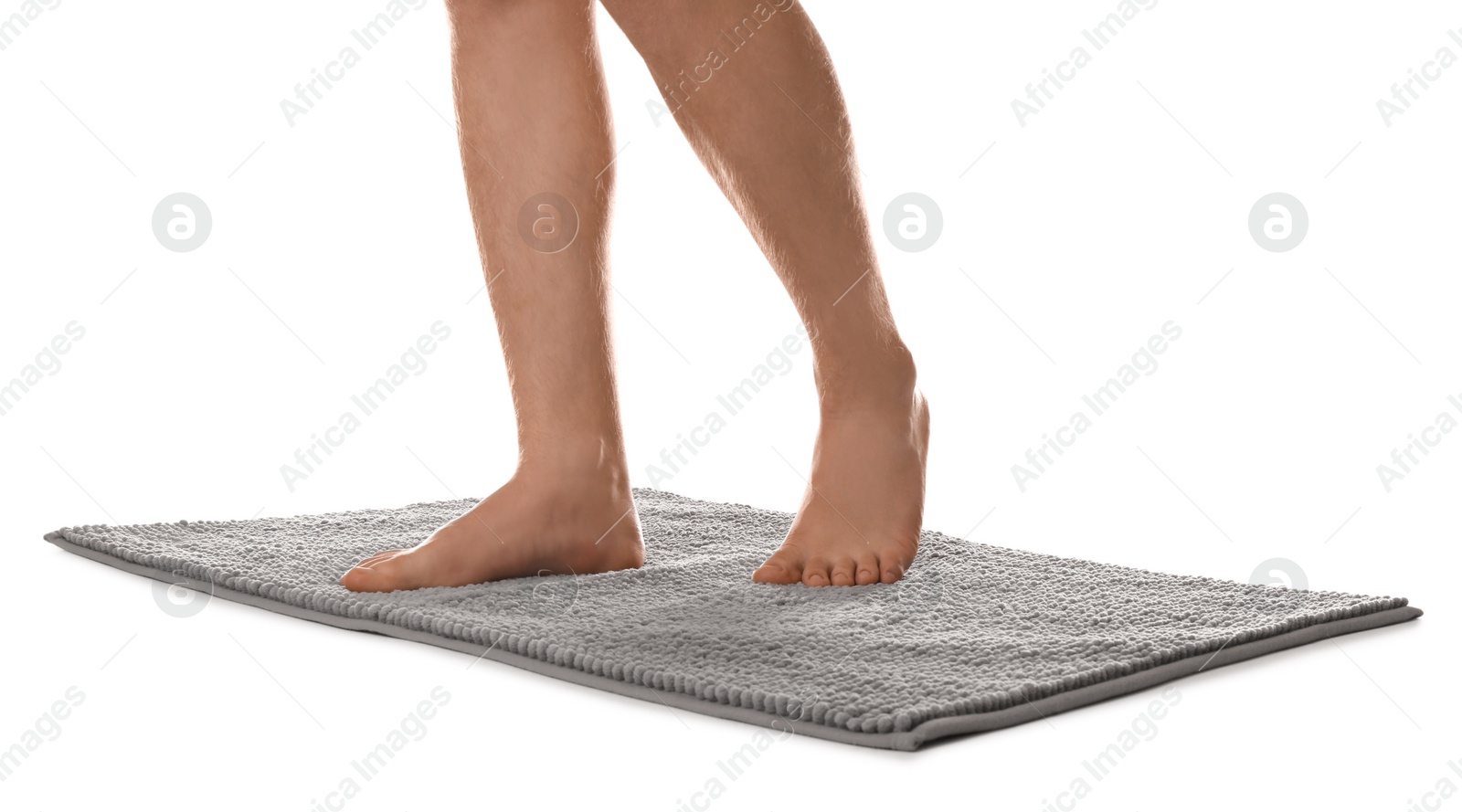 Photo of Man standing on soft grey bath mat against white background, closeup