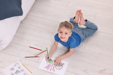 Photo of Cute little boy coloring on warm floor at home. Heating system