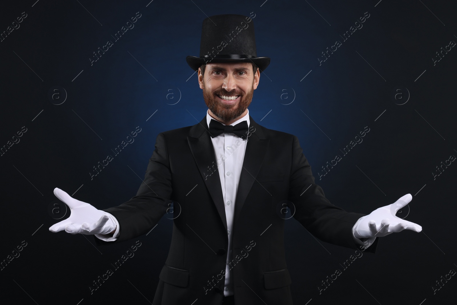 Photo of Happy magician in top hat on dark blue background