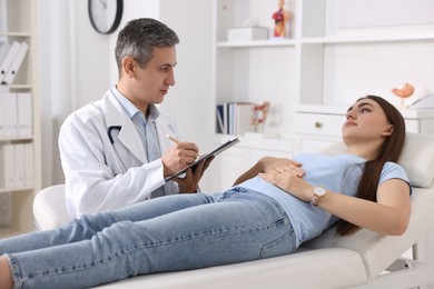 Gastroenterologist with clipboard consulting patient in clinic