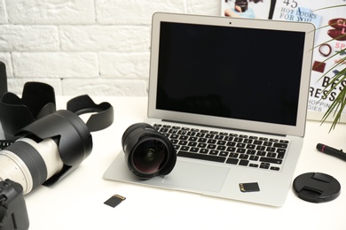 Photo of Laptop and professional photographer's equipment on table indoors. Space for text