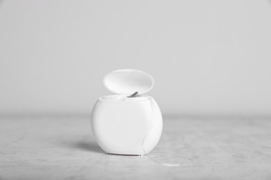 Container with dental floss on light grey textured table