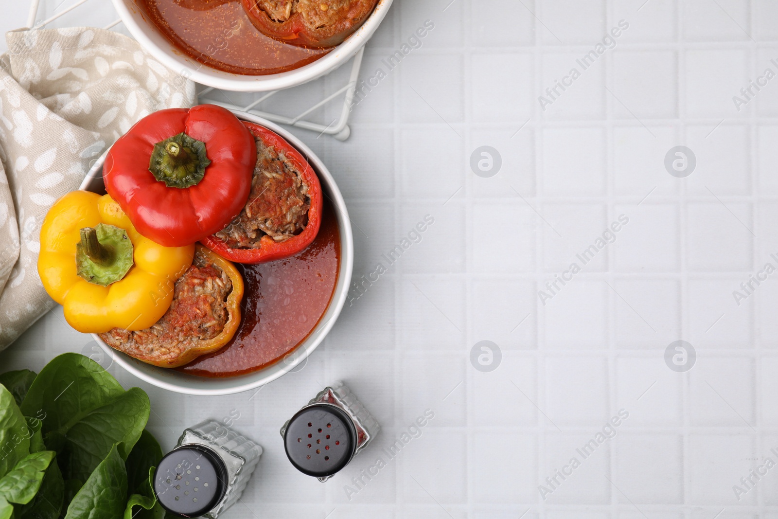 Photo of Delicious stuffed bell peppers on white tiled table, flat lay. Space for text