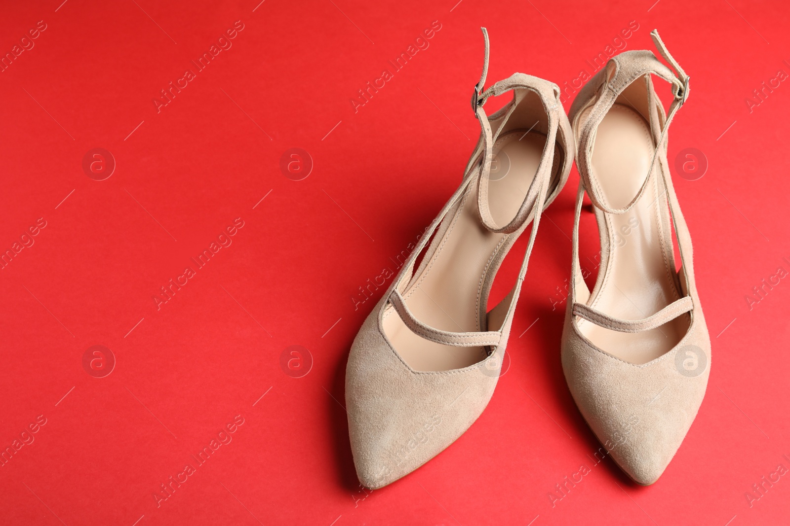 Photo of Stylish high heeled shoes on red background, space for text