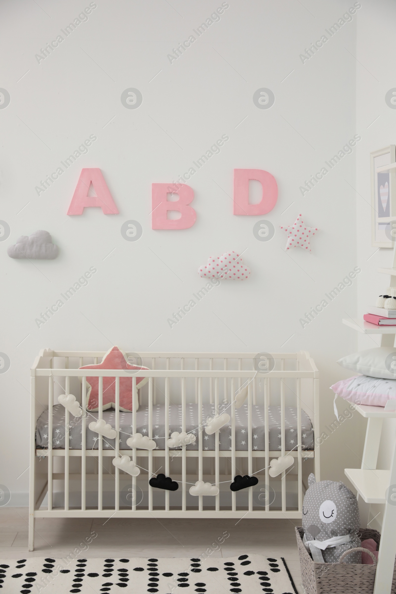 Photo of Cute baby room interior with modern crib near white wall