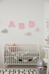 Photo of Cute baby room interior with modern crib near white wall