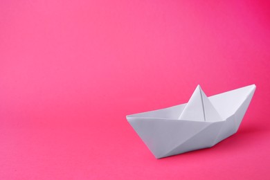 Photo of White paper boat on pink background, space for text. Origami art