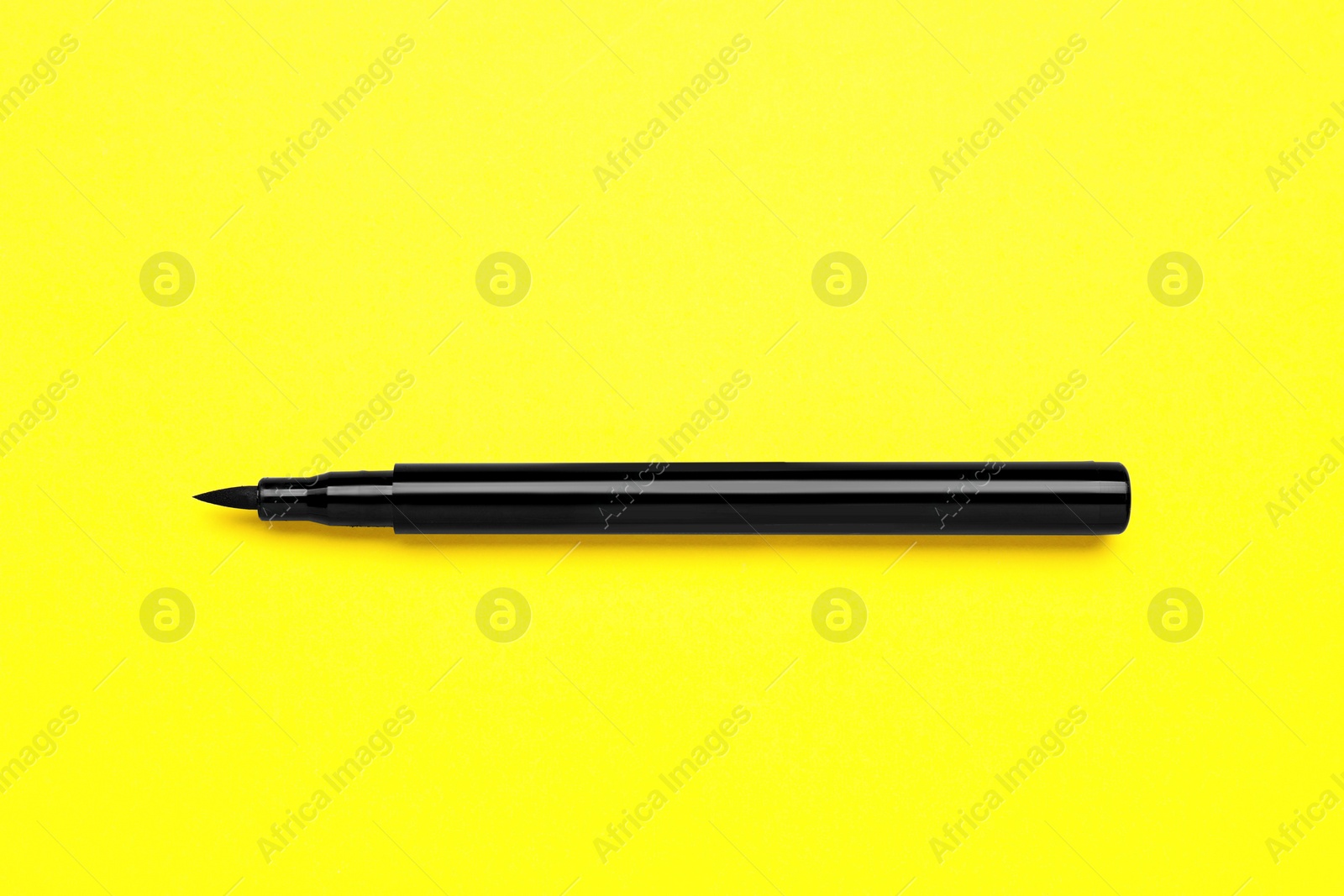 Photo of Eyeliner marker on yellow background, top view. Makeup product