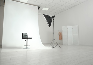 Photo studio interior with modern chair and professional lighting equipment