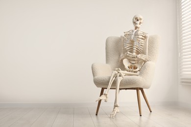 Photo of Waiting concept. Human skeleton sitting in armchair indoors, space for text