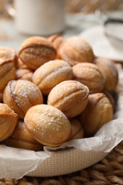 Photo of Bowl of delicious nut shaped cookies on wicker mat, closeup