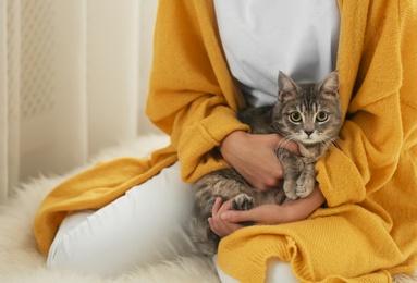 Photo of Young woman with cute cat at home, closeup. Cozy winter