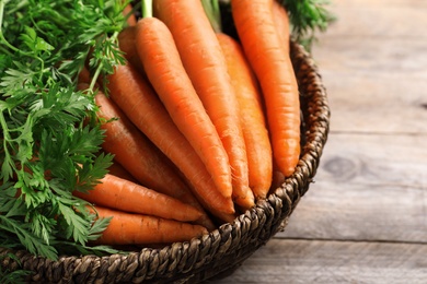 Photo of Basket of carrots on wooden background, closeup