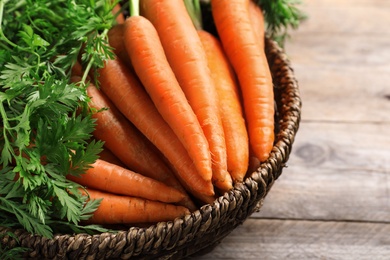 Basket of carrots on wooden background, closeup