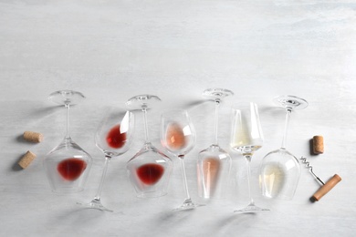 Different glasses with wine on light background, flat lay