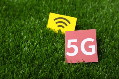 Photo of 5G technology, Internet concept. Cards with WiFi symbol on green grass, closeup. Space for text