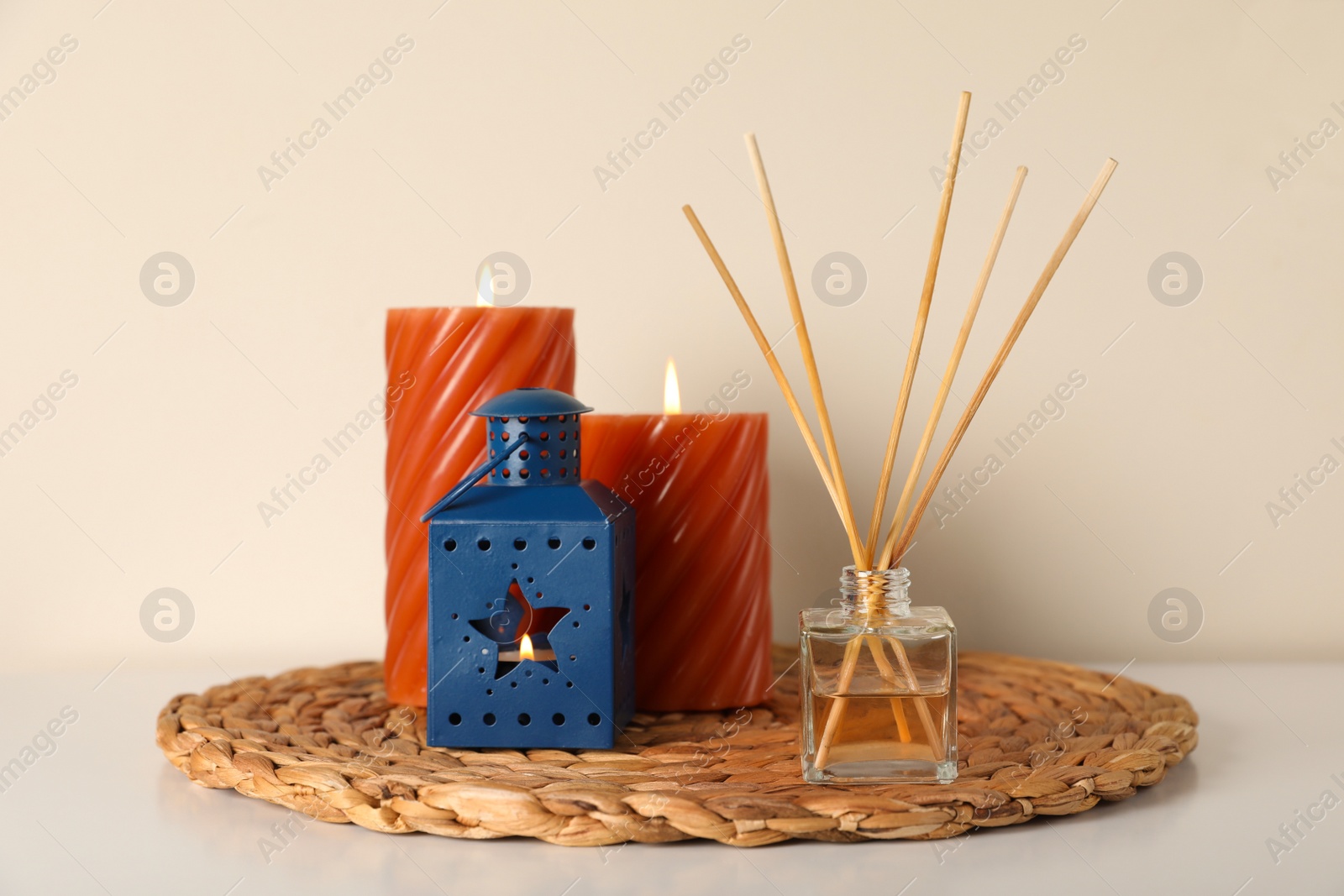 Photo of Aromatic reed air freshener and candles on white table indoors