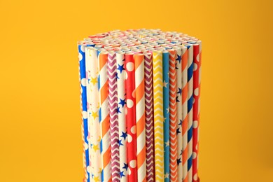 Photo of Many paper drinking straws on orange background, closeup