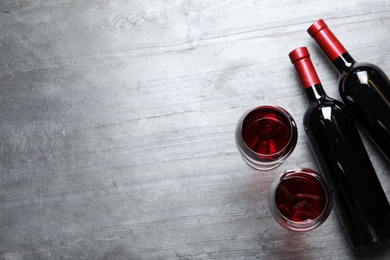 Glasses and bottles with red wine on color background, flat lay. Space for text