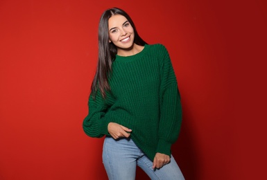 Happy young woman wearing warm sweater on red background 