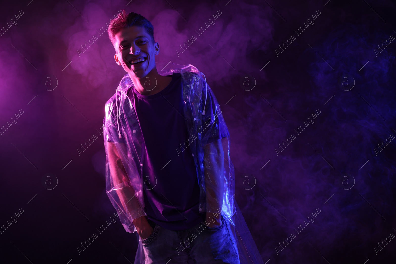 Photo of Young man wearing clear coat in neon lights with smoke effect. Space for text