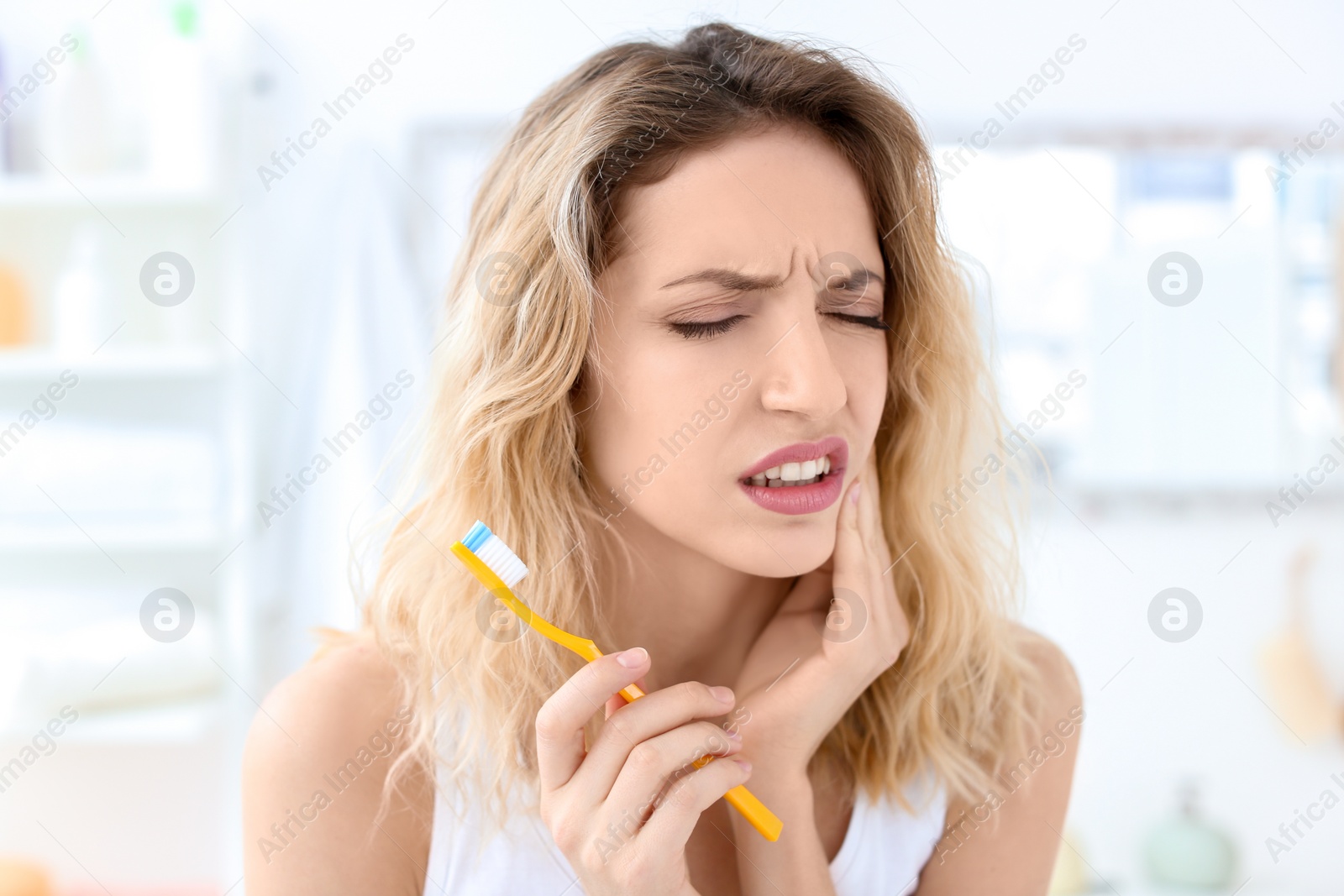 Photo of Young woman suffering from toothache indoors