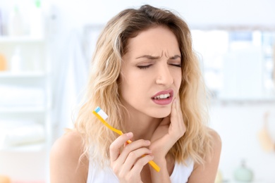 Photo of Young woman suffering from toothache indoors