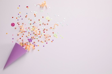 Photo of Colorful confetti and streamers with party cracker on white background, top view. Space for text